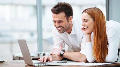 A male and a female working on the same laptop