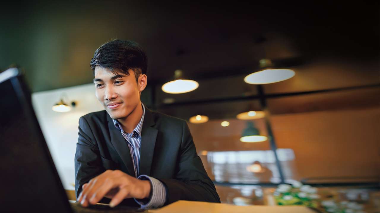 Smiling businessman in suit working with laptop